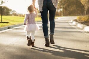 Mother walking with a toddler while holding her hand.