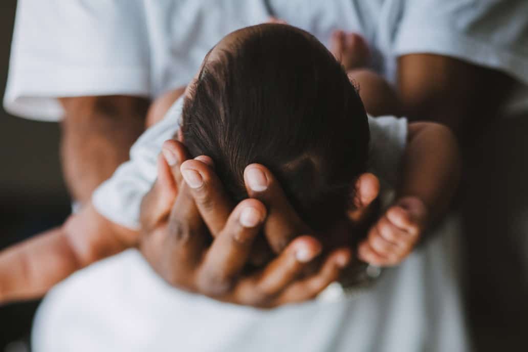 father holding the head of his baby.